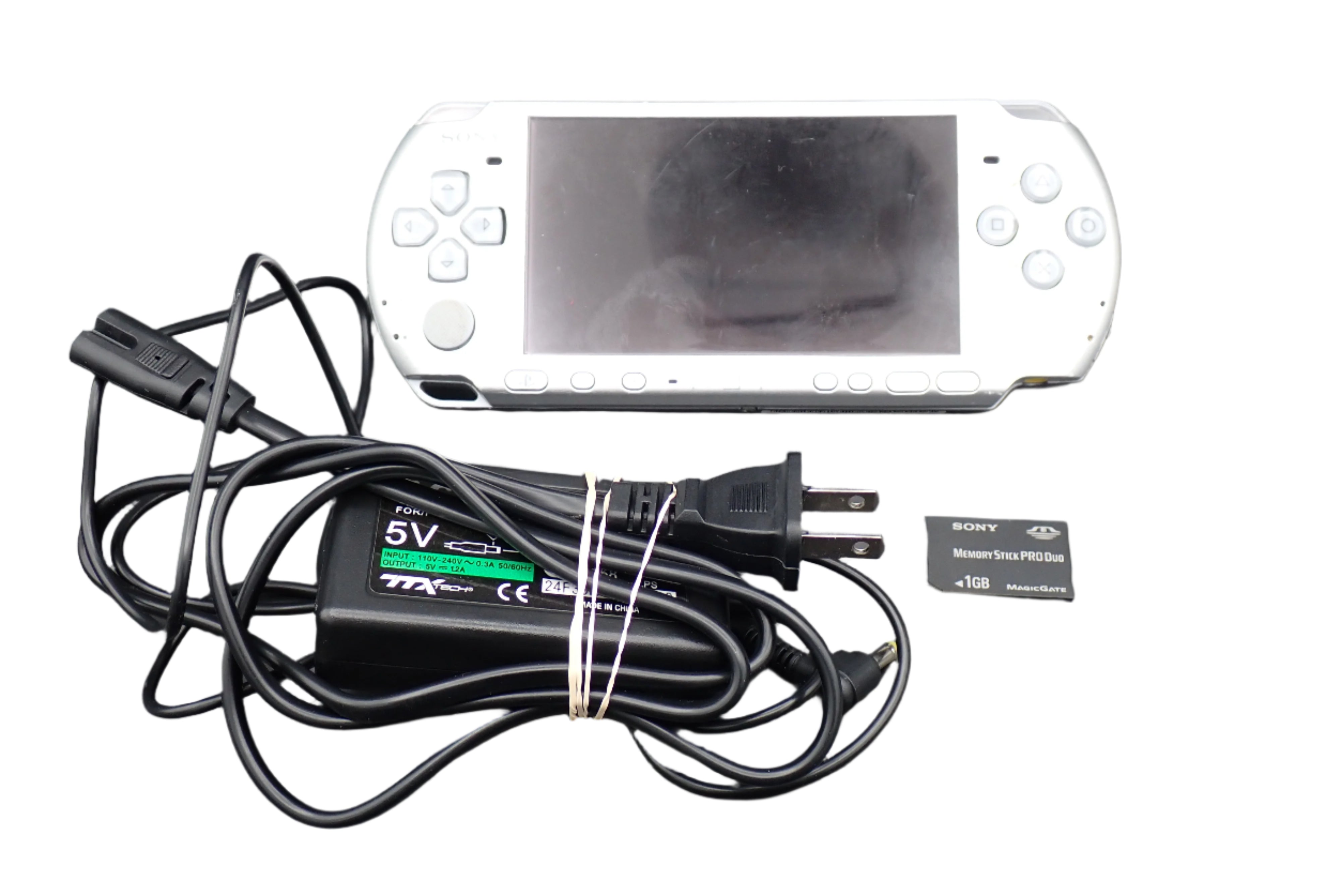 White handheld gaming console with charging cable and battery on a gray background