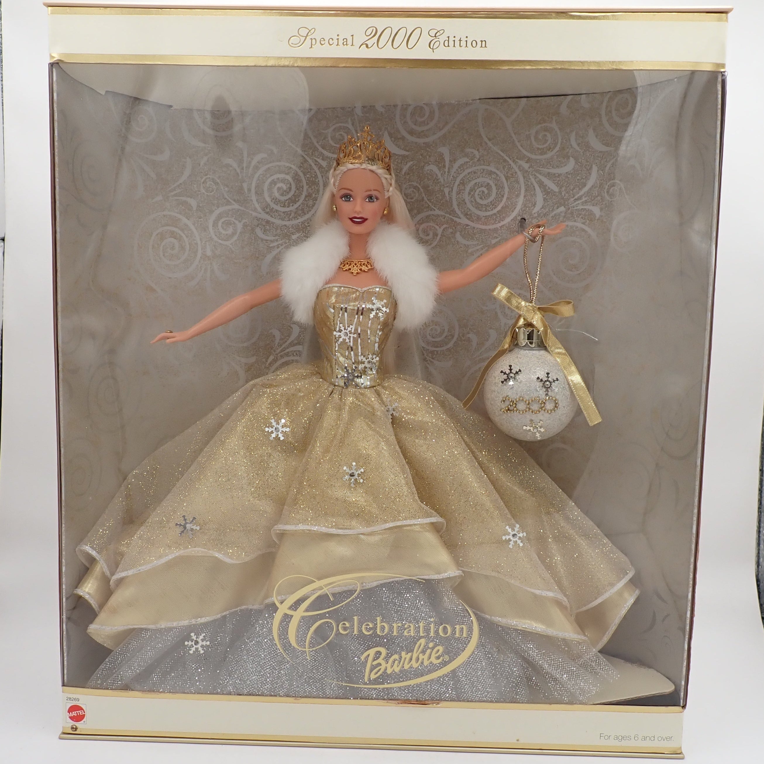 Barbie doll in a gold dress with a white fur coat in a box, labeled 'Celebration Barbie' Special 2000 Edition.